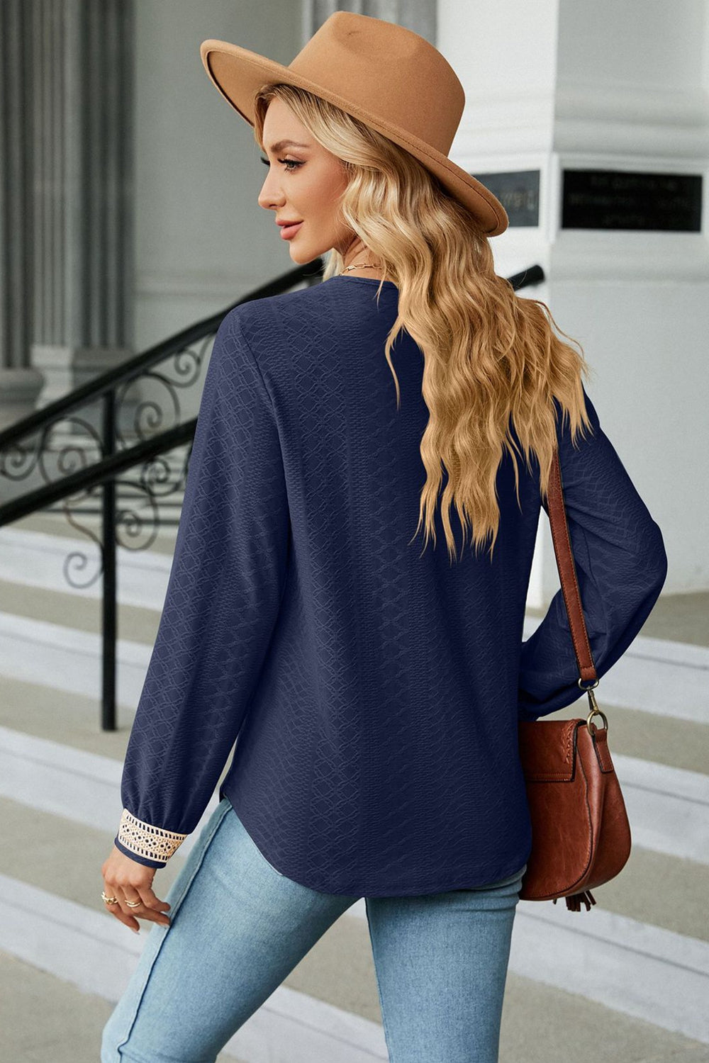 Dark blue textured blouse with V-neck and embroidered cuff detail.