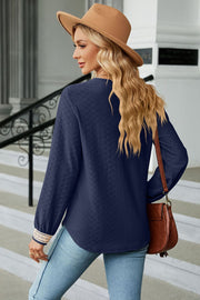 Dark blue textured blouse with V-neck and embroidered cuff detail.