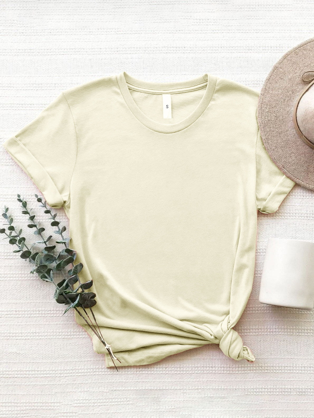 Light yellow oversized graphic tee with rolled sleeves and a knotted hem.