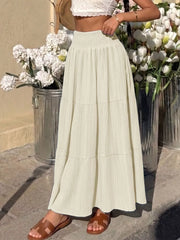 Smocked tiered maxi skirt in apricot with flowing elegance and textured fabric.