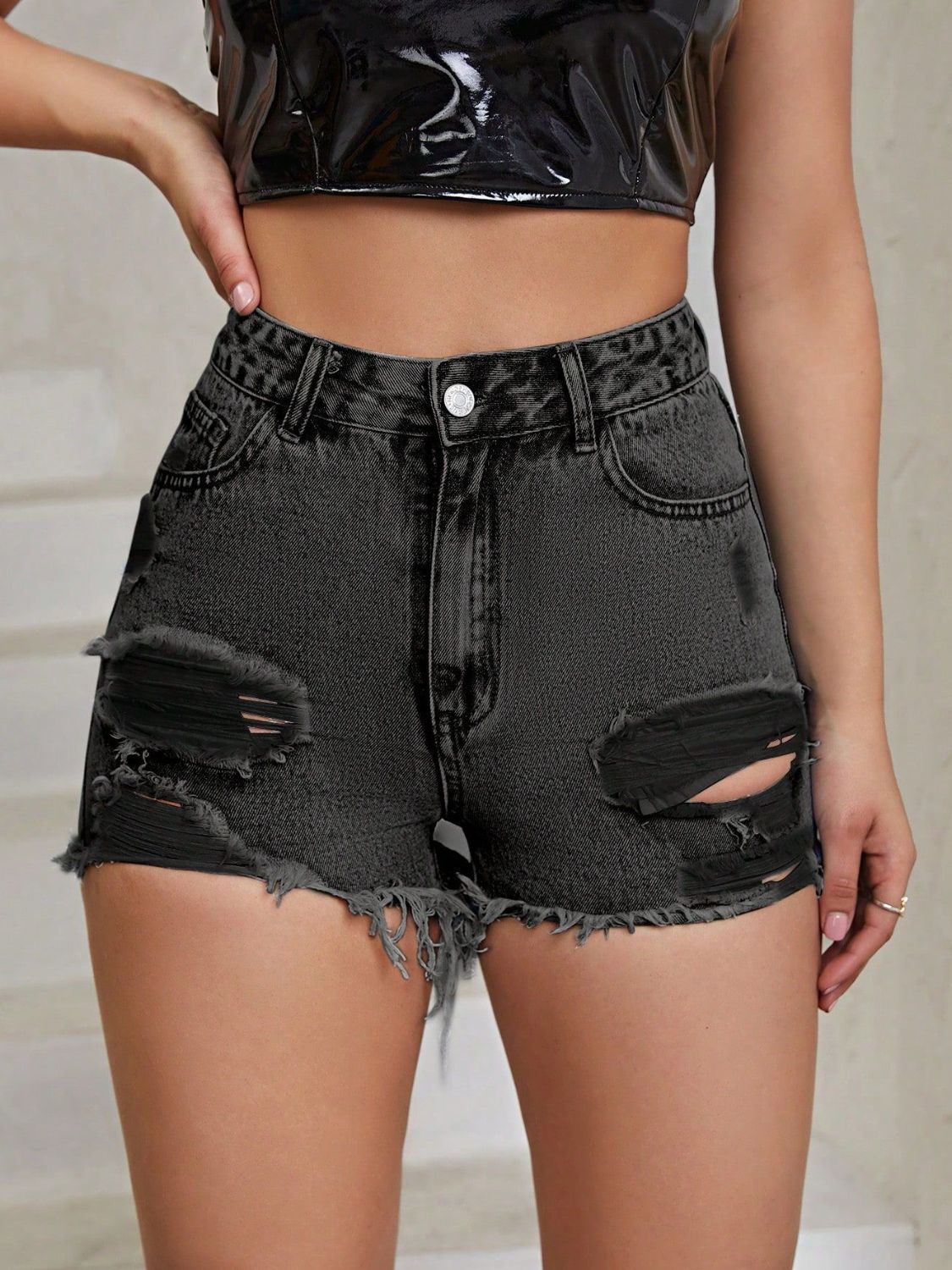 Distressed black denim shorts with frayed hem and ripped details.