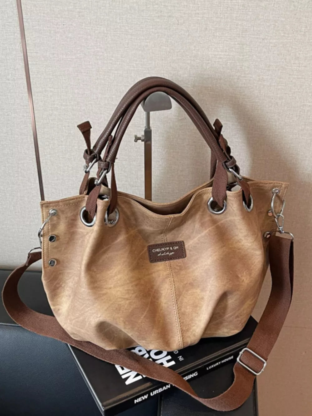 Slouchy crossbody bag in khaki with brown leather straps and adjustable strap.