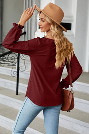 Burgundy textured puff sleeve blouse with ruffle cuffs and a square neckline.