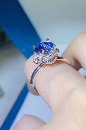 Blue moissanite cocktail ring with diamond halo and silver band.