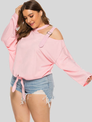 Blush pink cutout tie-front blouse with shoulder buckle detail and long sleeves.
