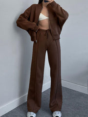 Brown zip-up bomber jacket and wide-leg sweatpants with drawstring waist and seam detail.