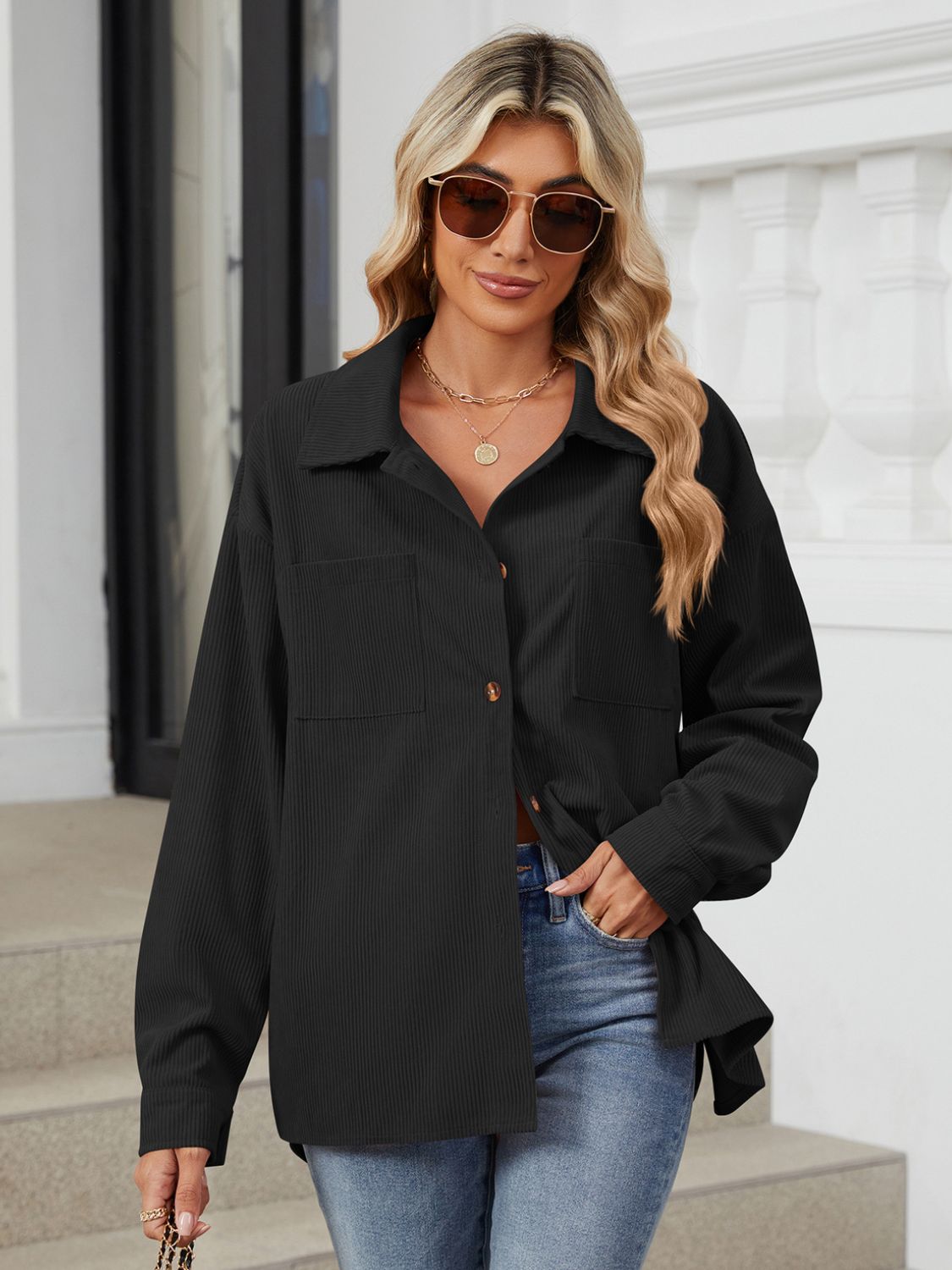 Black corduroy overshirt with buttoned patch pockets and a collared neckline.