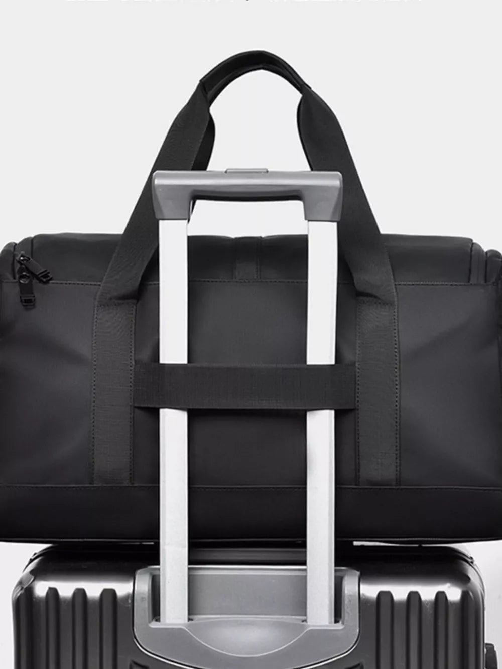 Black Oxford cloth travel bag with top handles and a luggage strap detail.