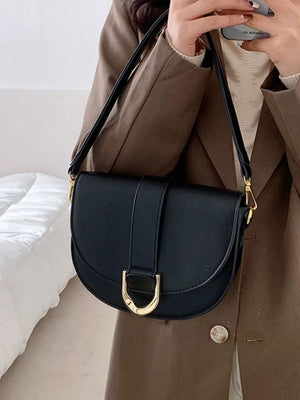 Chic semi-circular flap crossbody bag in black with gold hardware detail.
