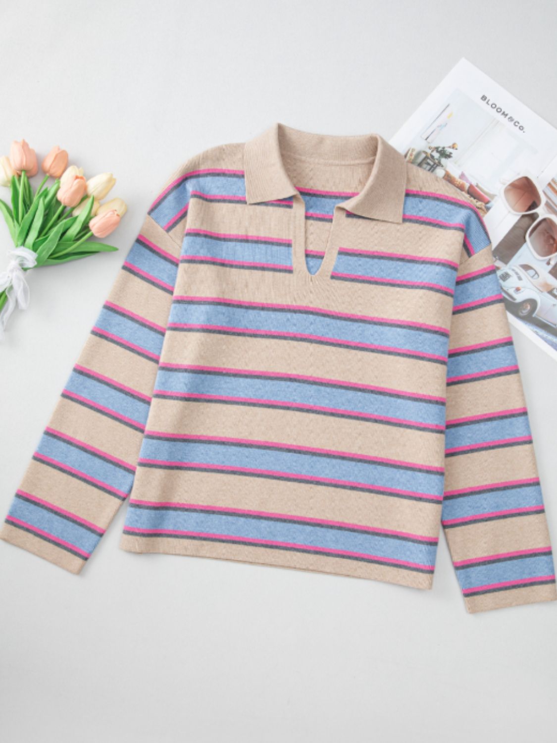 Beige striped knit polo sweater with deep V neckline and long sleeves.