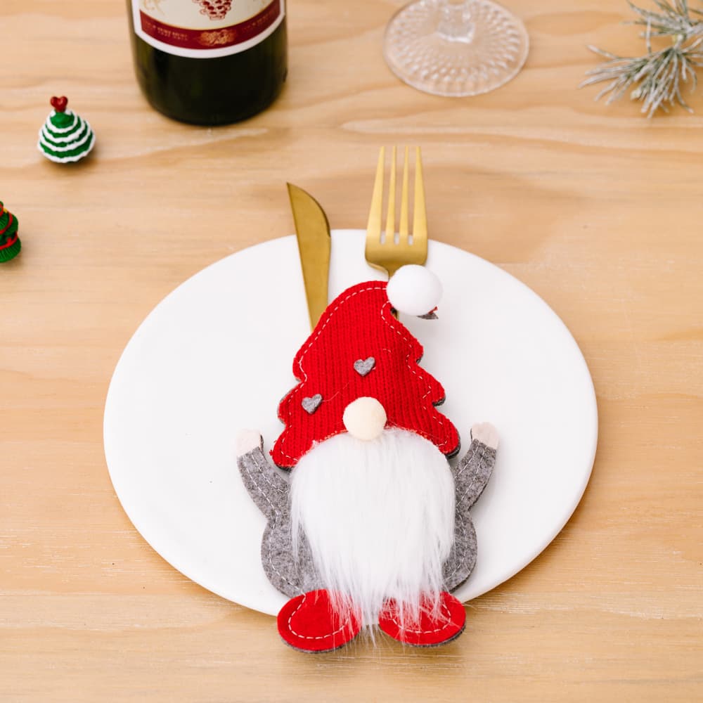 Red festive gnome cutlery accoutrement with white beard and grey arms on a plate.