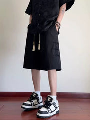 Black chino shorts with drawstring and toggle details, mid-length.