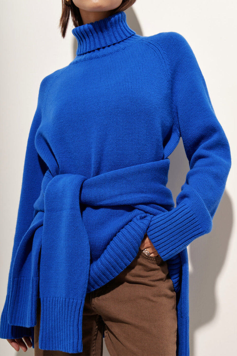 Royal blue cashmere turtleneck sweater with raglan sleeves and a tie waist detail.