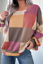 Multicolor patchwork waffle knit top with round neckline and long sleeves.