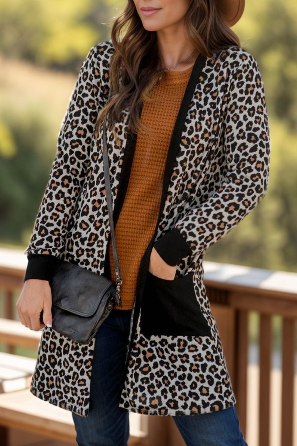 Leopard print cardigan with black contrast trim and pockets, worn open over a rust waffle knit top.