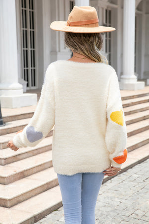 Ivory fluffy knit sweater with colorful heart patches on sleeves.