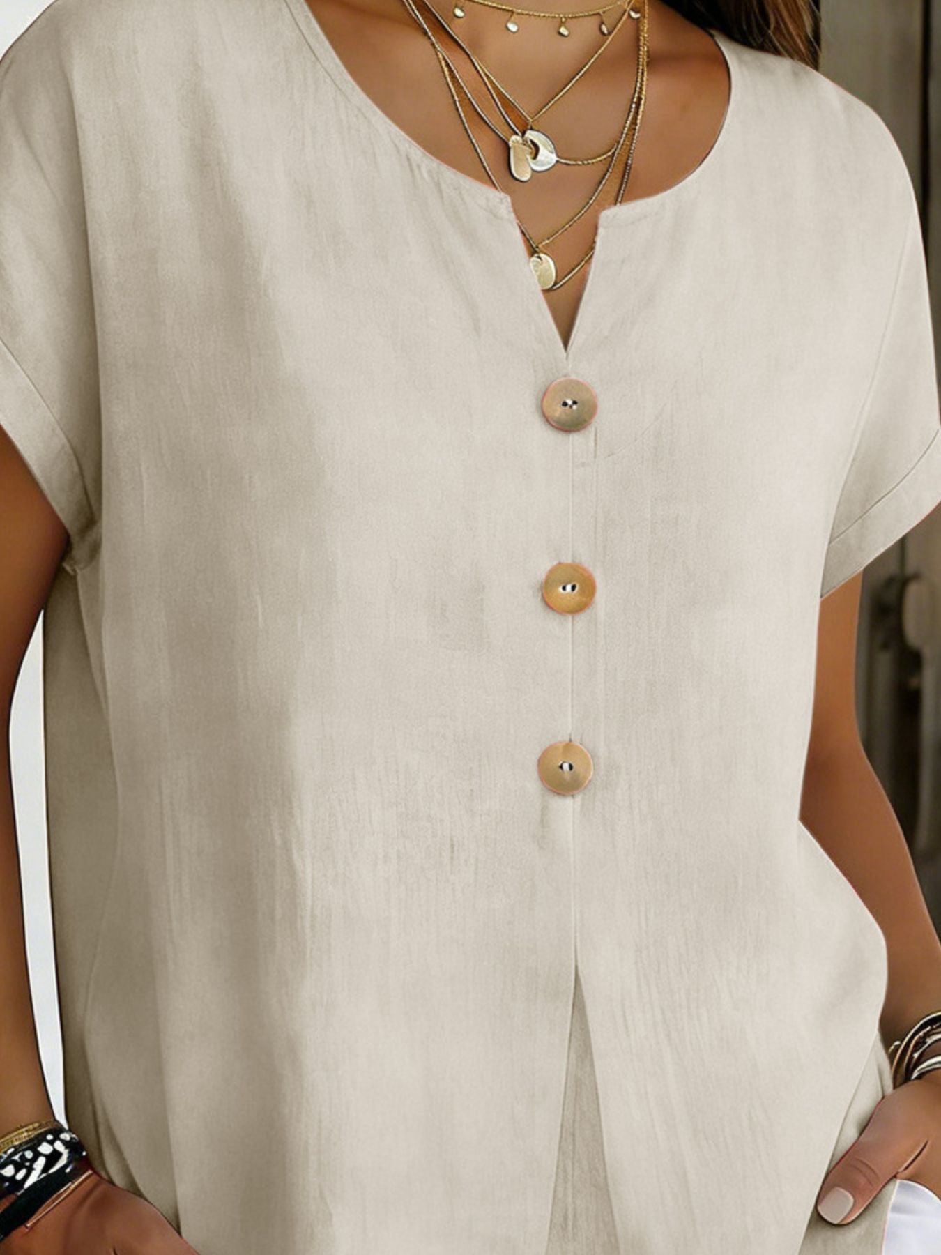 Beige buttoned short sleeve blouse with V-neck and wooden buttons.