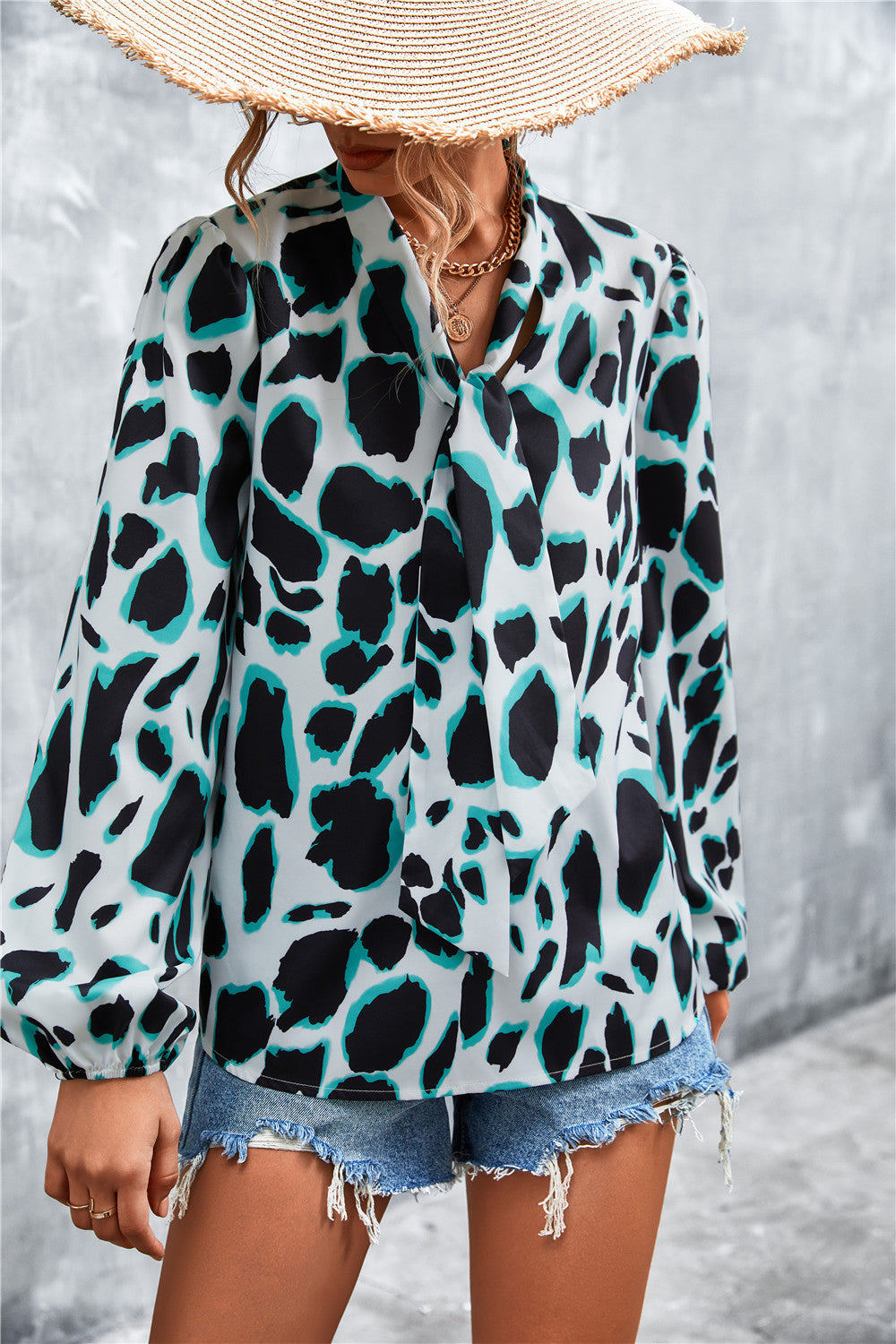 Women's abstract print pussy bow blouse in white with black and teal spots, balloon sleeves.