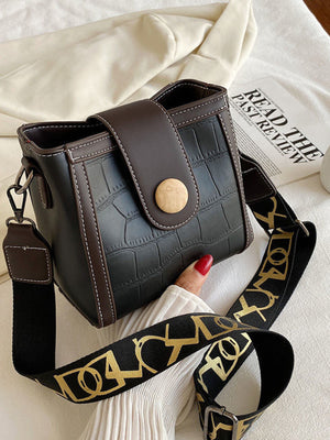 Black crocodile pattern mini crossbody bag with gold logo strap and wooden button closure.