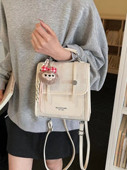 Chic mini flap backpack in white with plush charm and adjustable strap.
