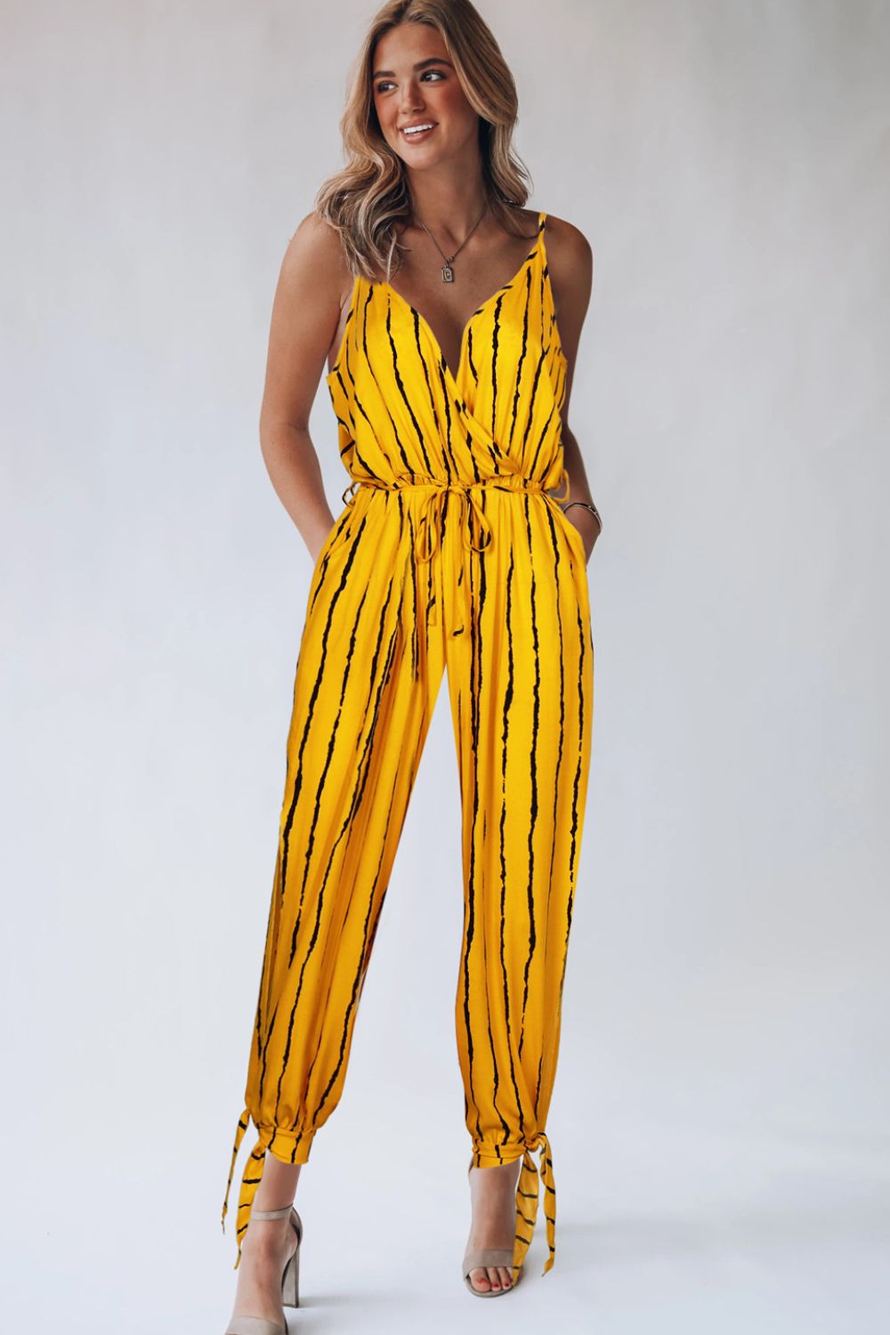 Gold striped wrap jumpsuit with tie ankles and V-neckline.