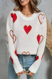 White knit crewneck sweater with allover red, pink, and brown heart motif.