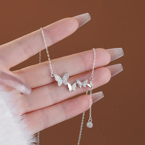 Delicate silver necklace with sparkling zircon butterfly charms and a dangling crystal accent.
