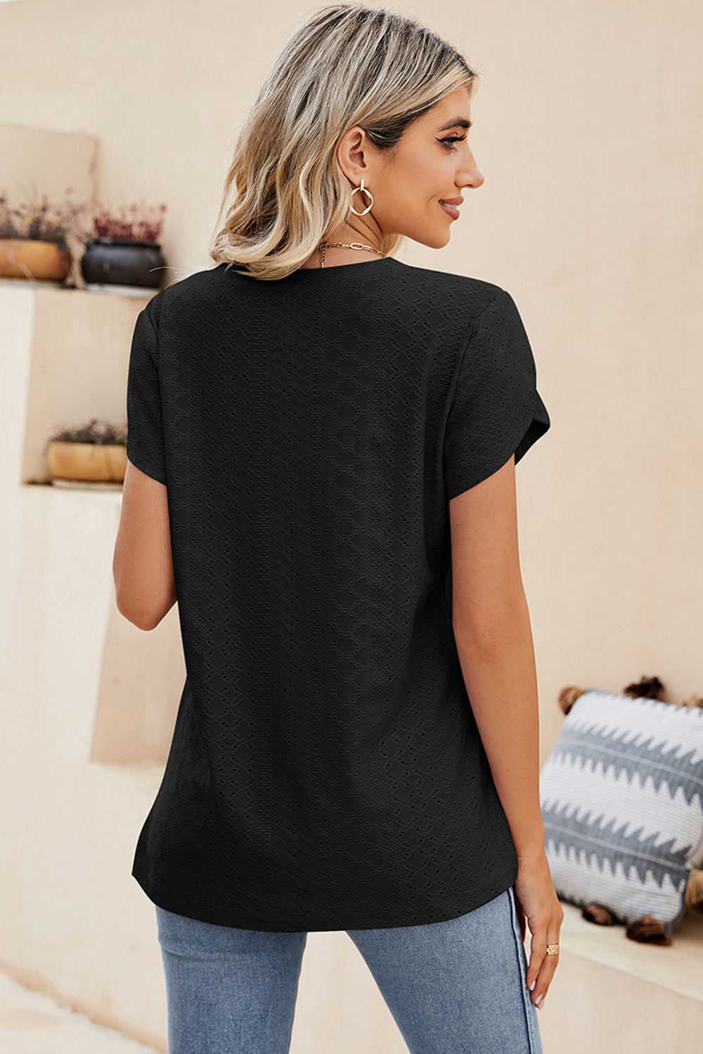 Black eyelet sleeve detail V-neck top with textured fabric.