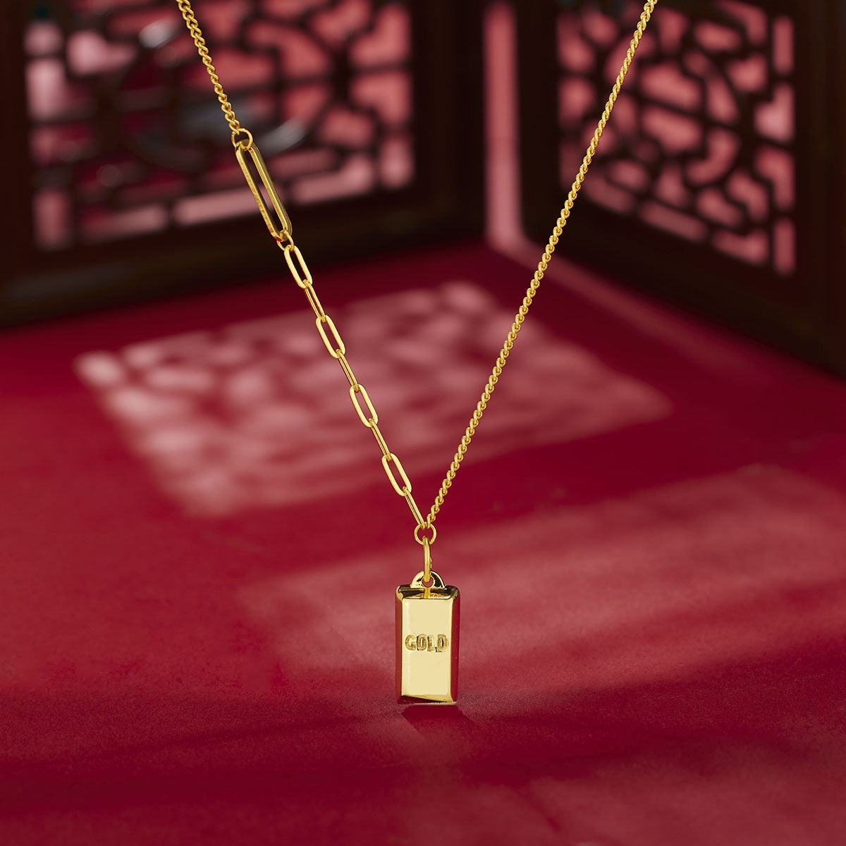 Gold-plated bar pendant necklace with curb link chain detail.