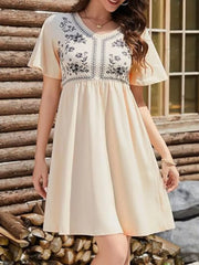 Embroidered floral v-neck mini dress in light yellow with short flutter sleeves and a gathered waist.