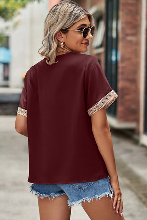 Burgundy V-neck blouse with lace trim on short sleeves.