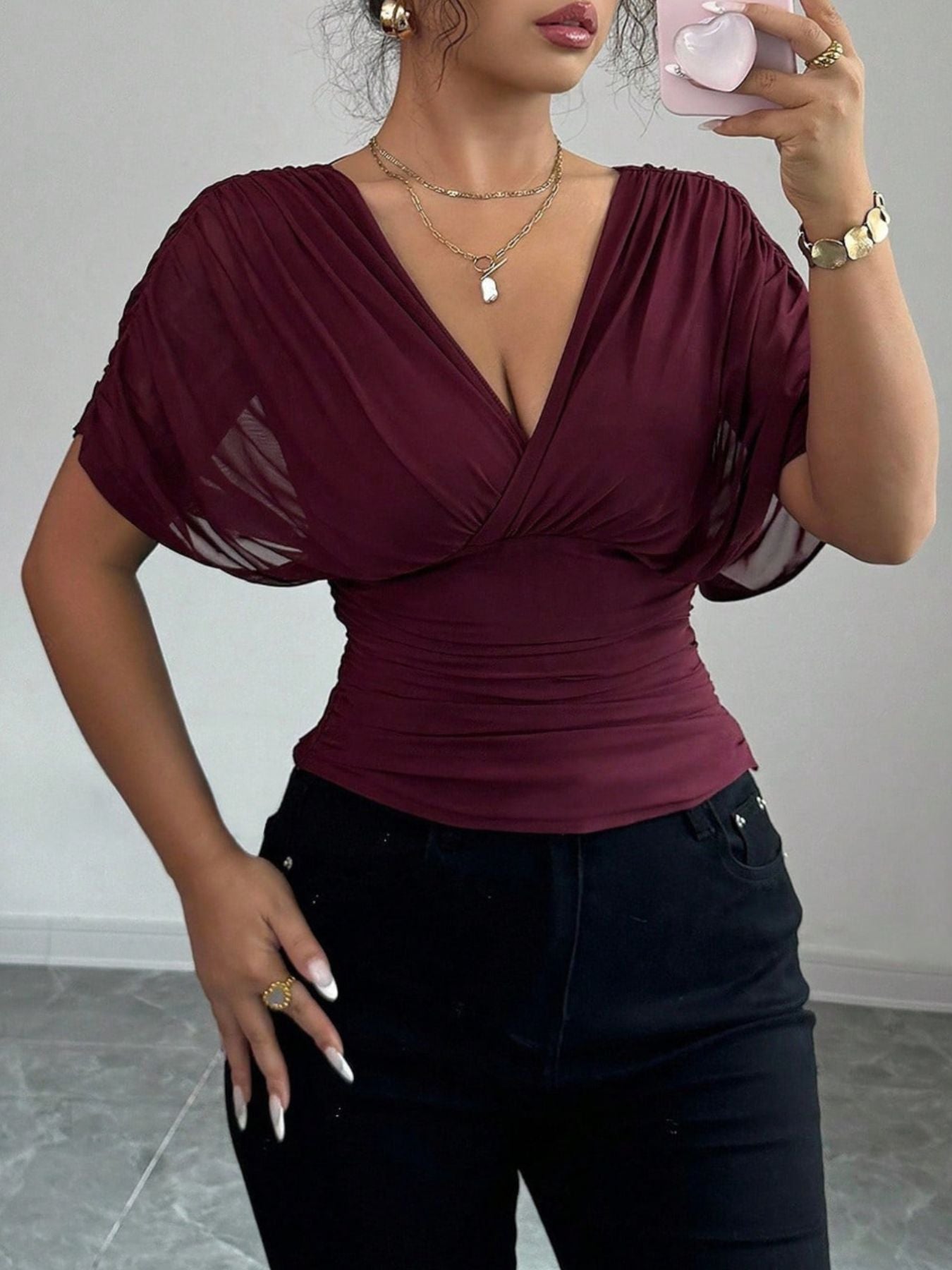 Burgundy ruched surplice dolman sleeve top with sheer sleeves and a deep V-neck.