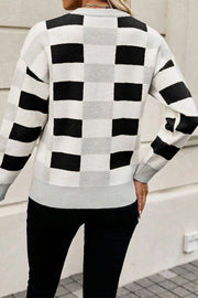 Off-shoulder knit pullover sweater with black and white checkerboard pattern.