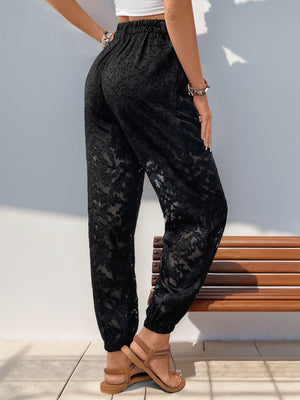 Black textured lace joggers with elastic waistband and cinched cuffs.