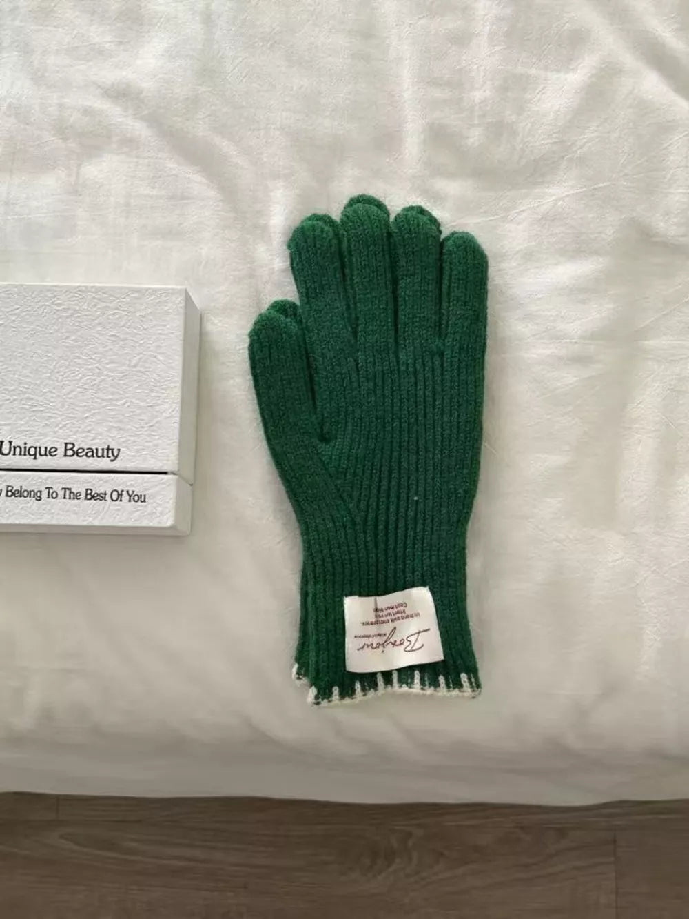 Dark green ribbed knit gloves with scalloped cuff detail and white trim.
