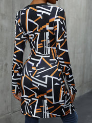 Geometric print long sleeve blouse with asymmetric hem and black neckline.