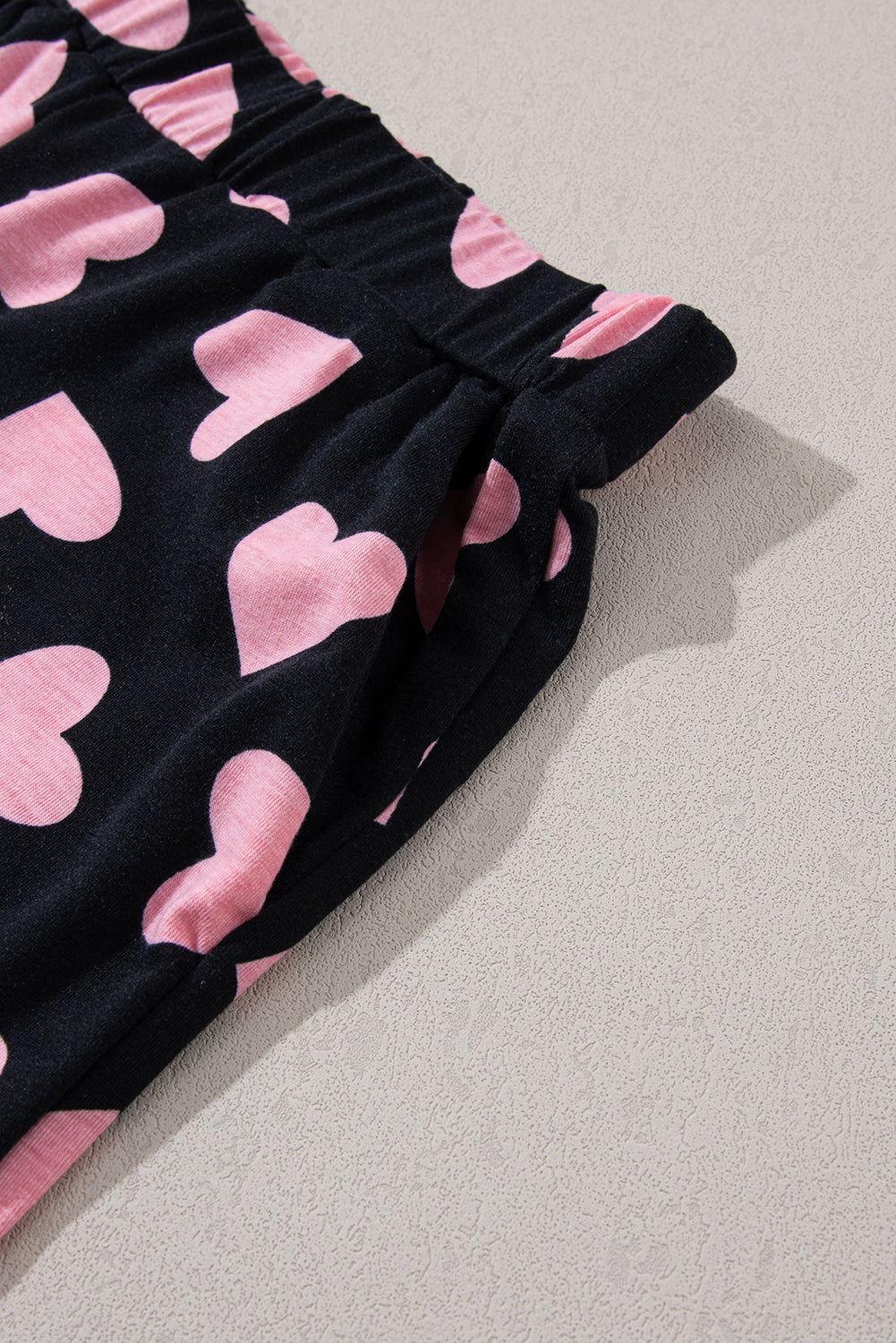 Black lounge set pants with pink heart print and elastic waistband with pockets.