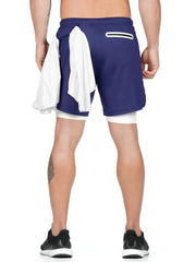 Royal blue layered performance shorts with white built-in compression shorts and a white towel draped over the left side.