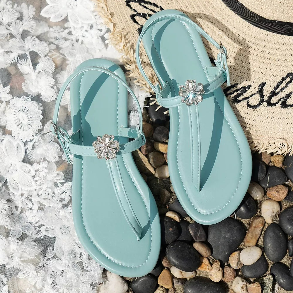 Lake blue flat sandals with floral gem embellishments and ankle straps.