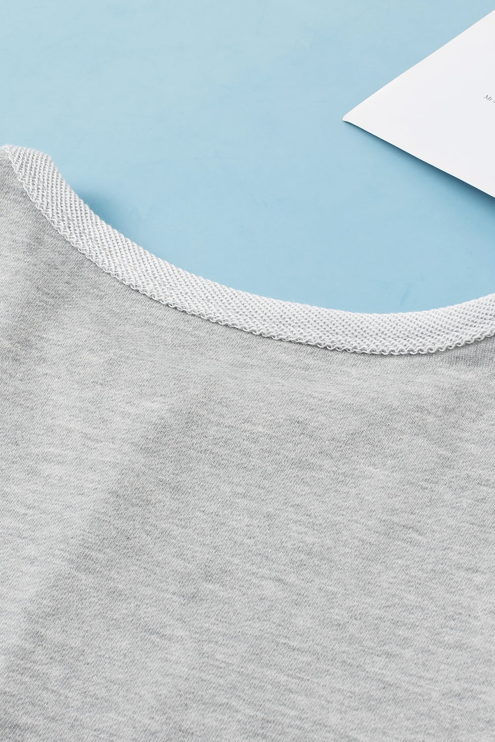 Light gray sweatshirt with a textured crew neck detail.