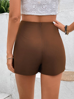 Brown high-waist shorts with an asymmetric wrap-front detail and a back zipper.