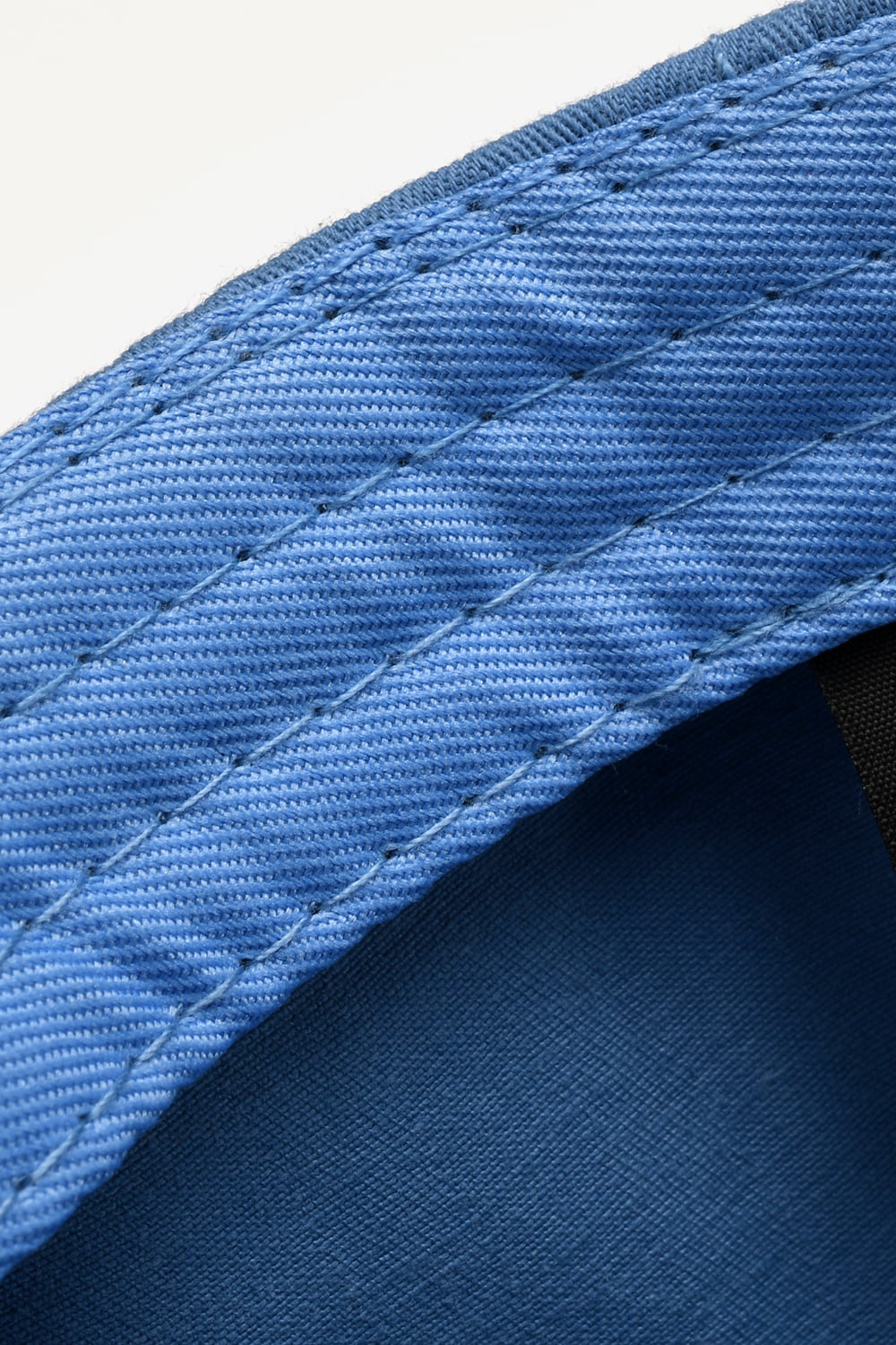 Cobalt blue denim baseball cap detail with raw edge and contrast stitching.