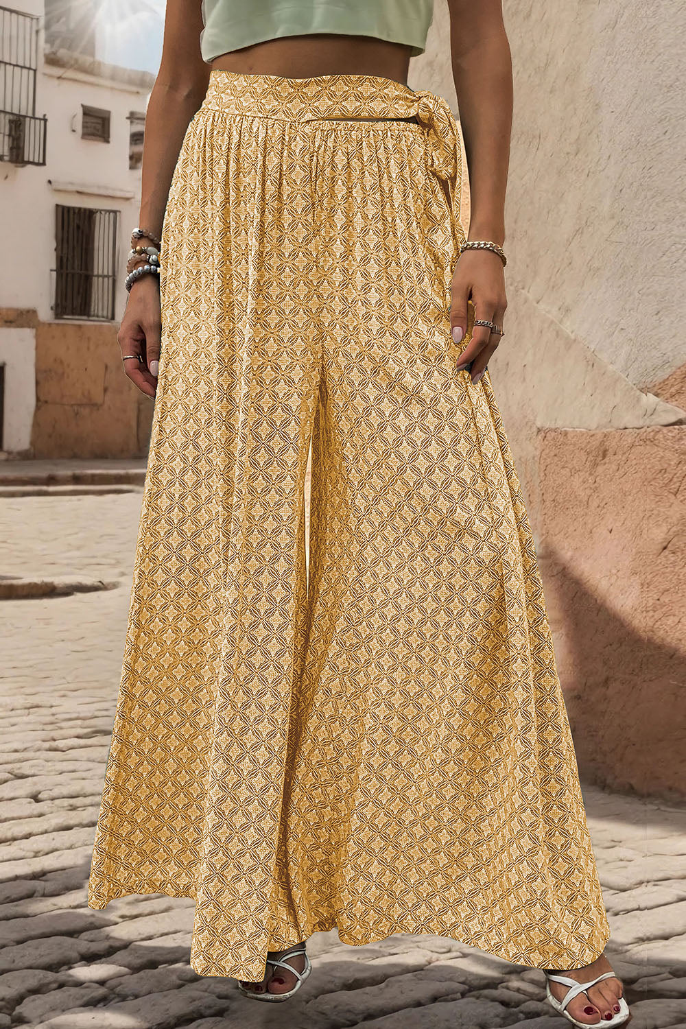 Yellow wide-leg palazzo trousers with geometric print and tie waist detail.