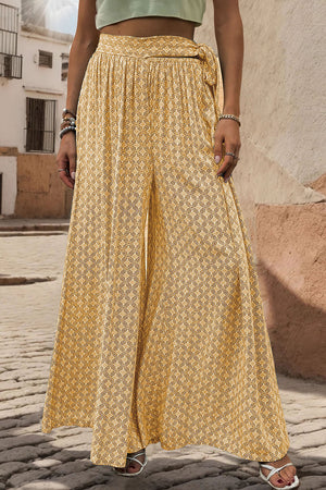 Yellow wide-leg palazzo trousers with geometric print and tie waist detail.