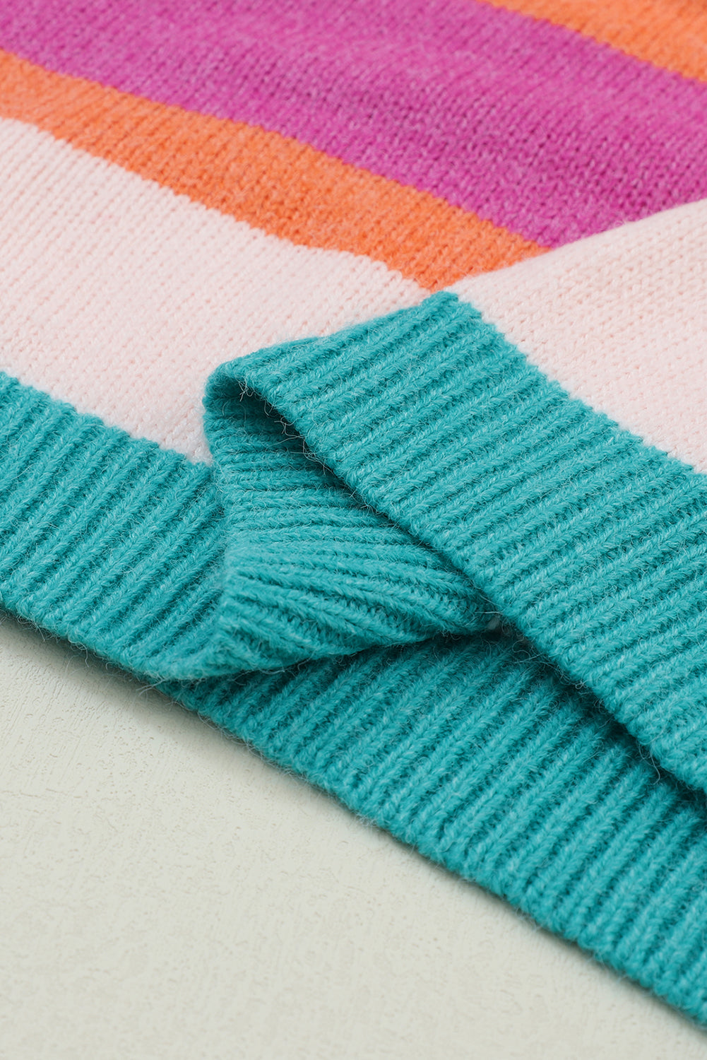 Rainbow stripe knit sweater with teal ribbed trim and balloon sleeves.