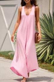 Pink wide leg jumpsuit with V-neck and pockets, styled with a straw bag.