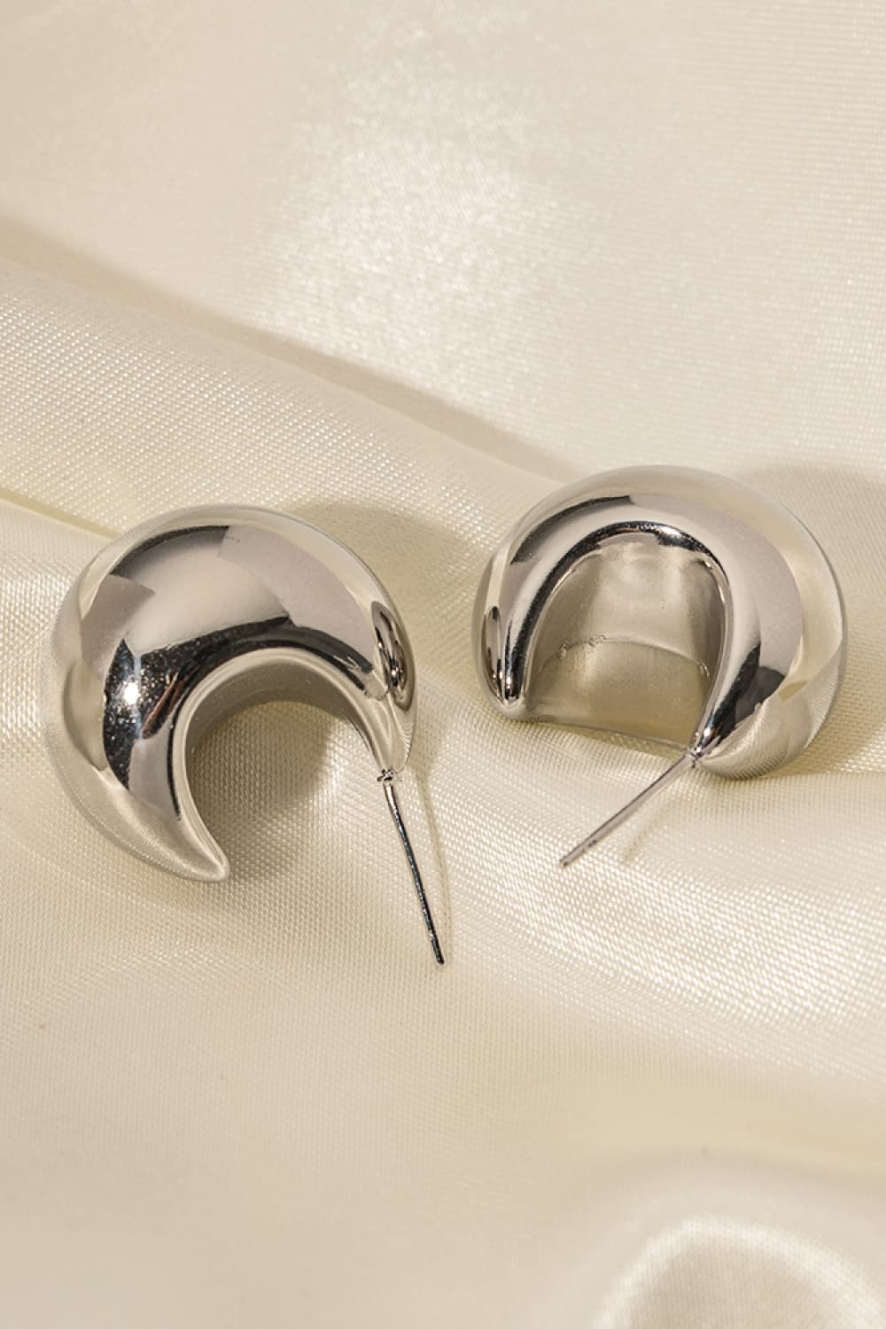 Sculptural silver crescent hoop earrings with a polished finish.