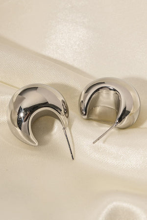 Sculptural silver crescent hoop earrings with a polished finish.
