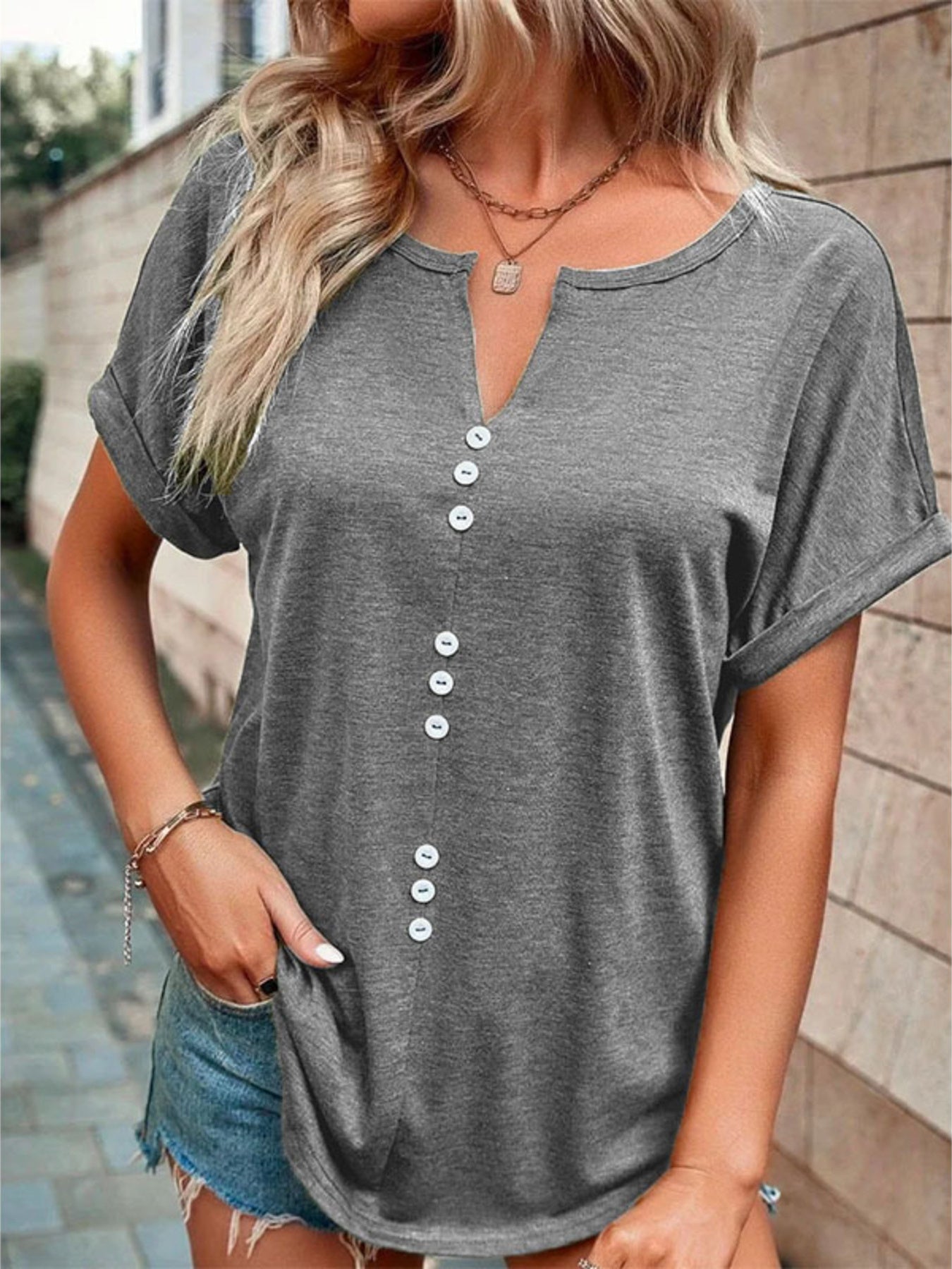 Grey short sleeve t-shirt with V-neck and decorative buttons.