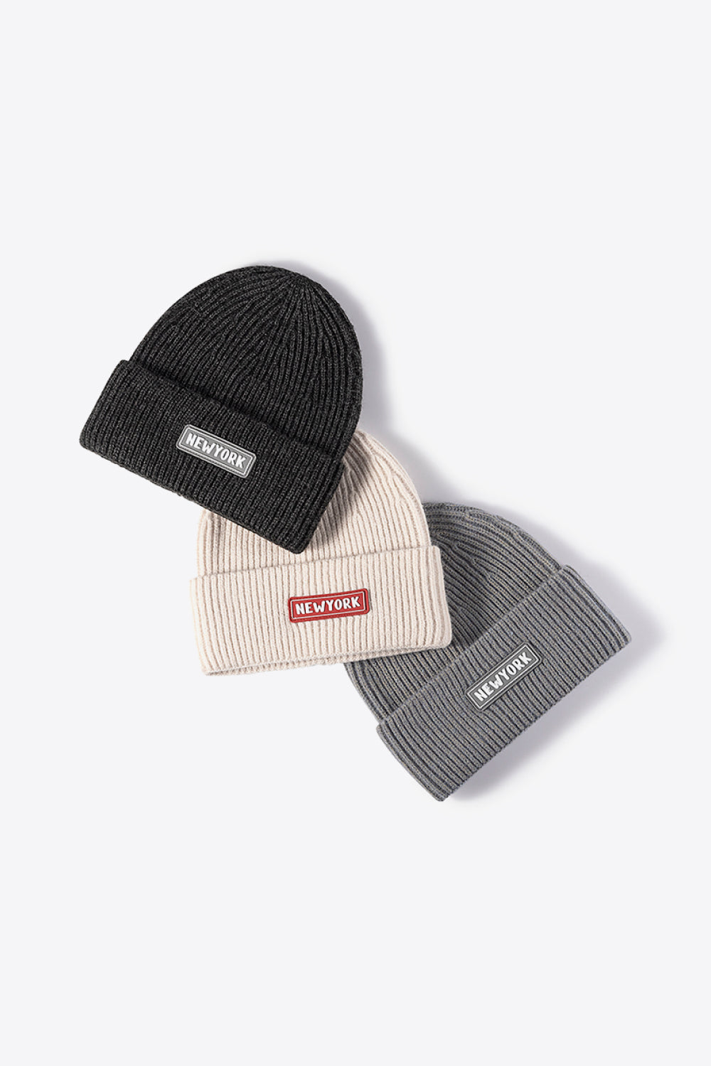 Ribbed acrylic beanies in black, beige, and gray, each with a New York patch detail.